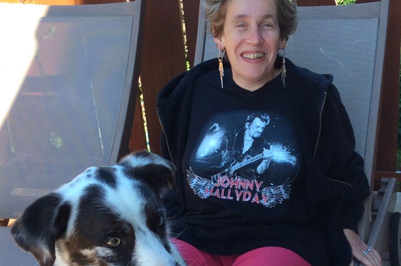 Evelyne Ramelet est installée dans une chaise longue, sur sa terrasse, avec un chien.