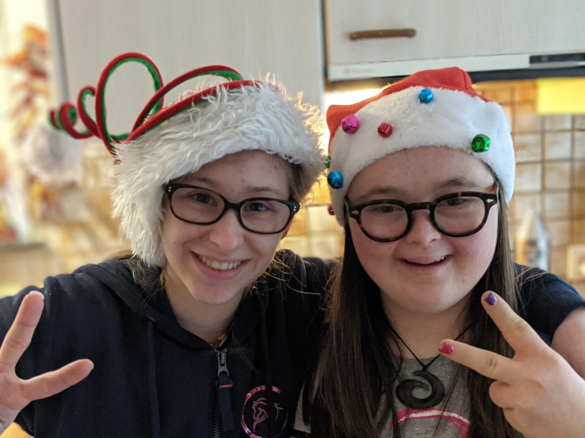 Zwei junge Frauen mit Weihnachtsmannmützen lächeln.
