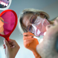 Une femme dentiste traite un patient qui a la bouche ouverte.