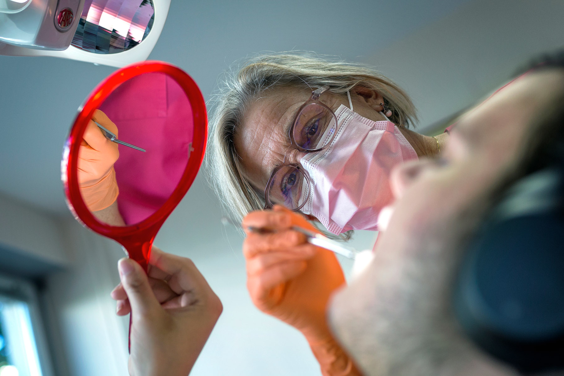 Une femme dentiste traite un patient qui a la bouche ouverte.
