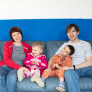 La famille assise sur un canapé bleu dans l'espace commun du centre d'accueil où elle vit.