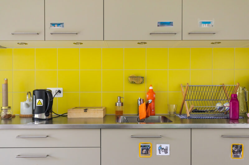 Eine gelbe Küche mit Piktogrammen auf den Schränken.