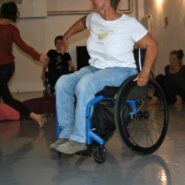 Un groupe de personnes, dont une femmes en fauteuil roulant, dansent.